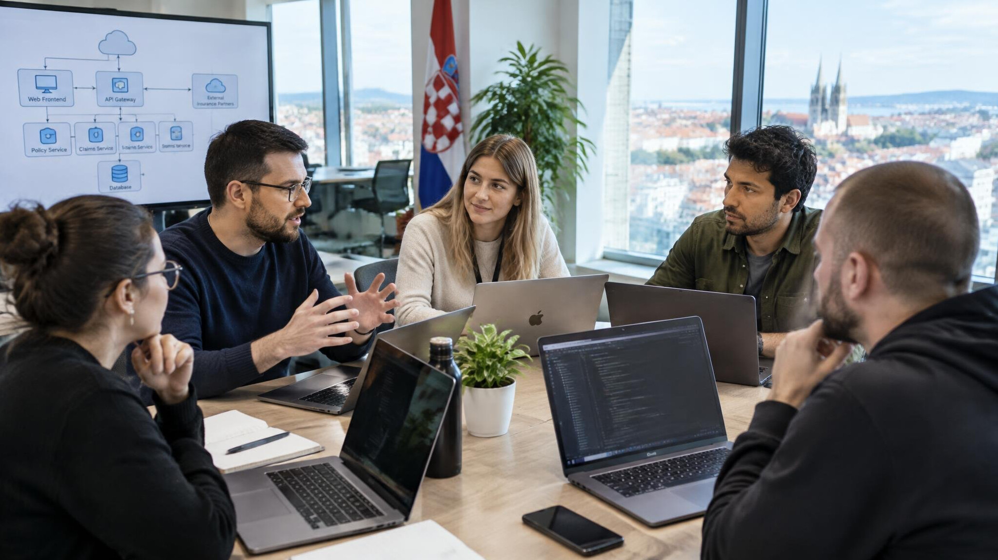 Team of Croatian software engineers collaborating around laptops in office